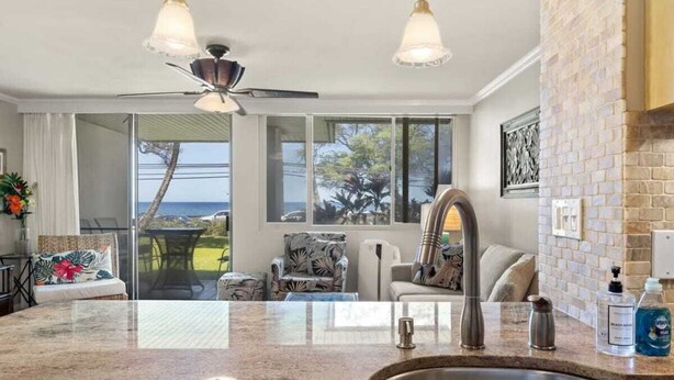Una cocina moderna con una isla grande, pileta de acero inoxidable e iluminación colgante.