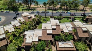 Zona residencial con varios tejados, una calle con coches y una playa al fondo.