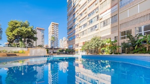 A swimming pool surrounded by high-rise buildings, reflecting the architecture and trees. - Karola Apartment 12-C Levante Beach (Benidorm)
