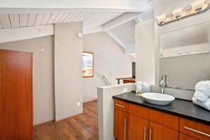 Um banheiro moderno com toucador de madeira, um espelho grande e um lustre no teto.