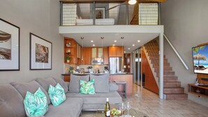 A spacious living area with a sofa, a glass coffee table, and a kitchen in the background. - Papakea Villas | Ocean View 3 BR Sleeps 8 | Car Incl. w/ 6+ Nights | PKC-404 by KBM (Lahaina)