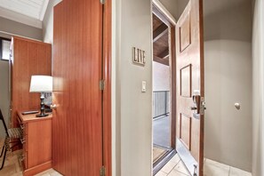 Une chambre d’hôtel avec une armoire en bois, une table de chevet avec une lampe et un panneau indiquant « EN DIRECT ».