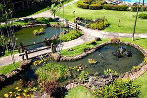 Um jardim paisagístico com vários lagos, uma ponte e gramados bem cuidados.
