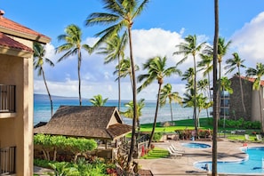 A resort with a pool, palm trees, and a view of the ocean.
