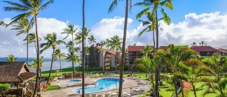 A resort with a pool, palm trees, and ocean views.