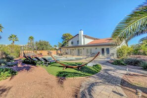 Una casa con piscina, hamaca y zona de patio.