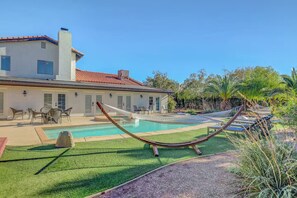 Una piscina con una hamaca, mobiliario exterior y un césped bien cuidado.