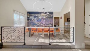 Ett modernt matområde med en väggmålning som föreställer stadens silhuett, en modern lampa och utsikt över staden genom ett stort fönster.