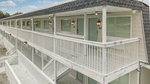 A row of beachside cabins with individual porches and windows, each with a door number. - Dockside Inn (Deltaville)