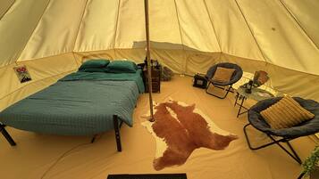 A tent with a bed, a chair, a rug, and a cowhide rug.