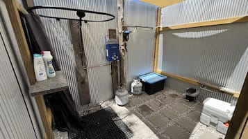 Un baño pequeño con ducha, calentador de agua y un contenedor de almacenamiento.