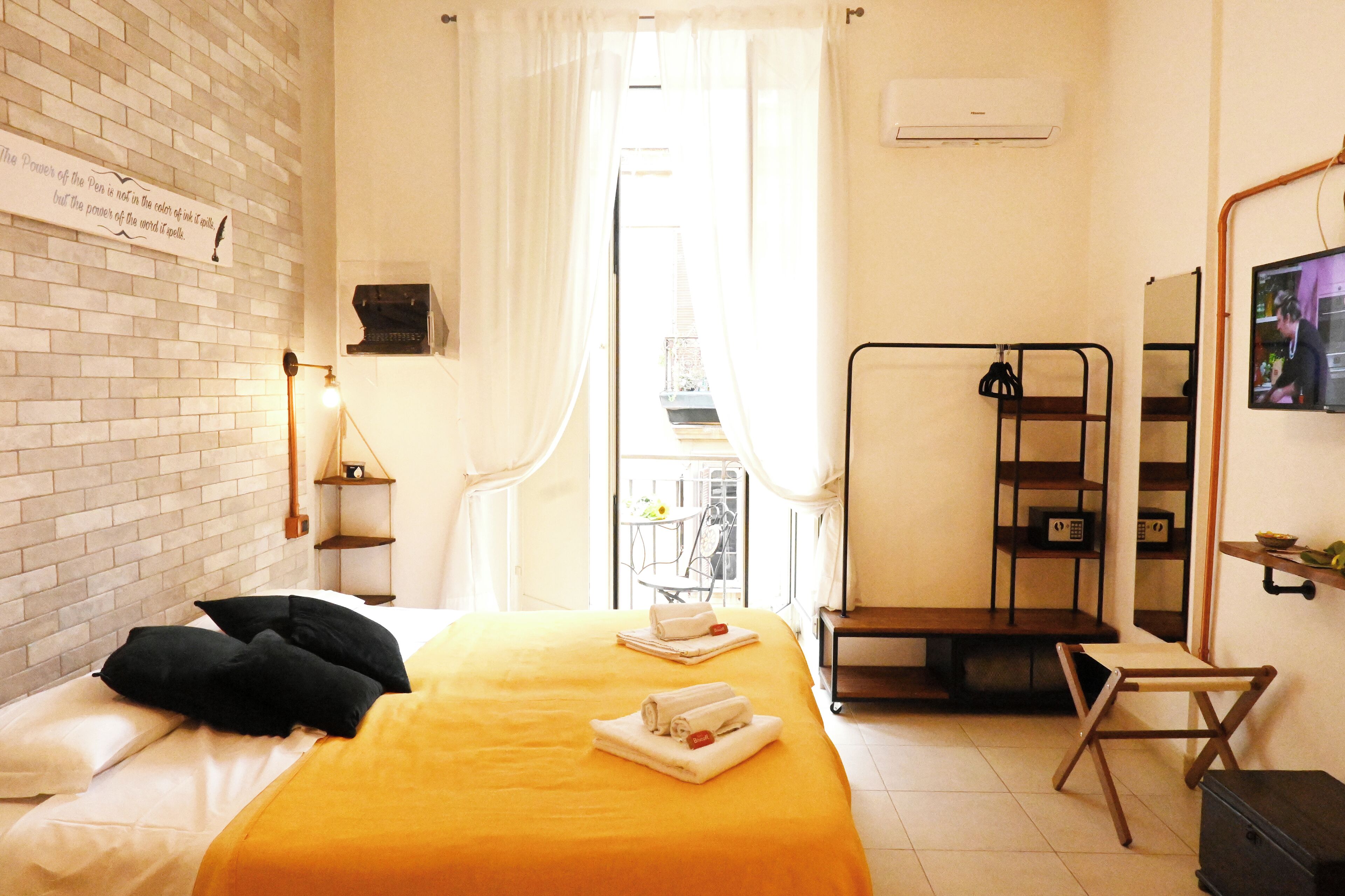 Une chambre d’hôtel avec un lit, une petite table, une chaise, un miroir et une vue sur l’extérieur.