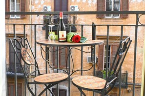 A balcony with two round tables and chairs, a bottle of wine, a glass, and a bouquet of flowers. - Napoli Cityscape (Naples)