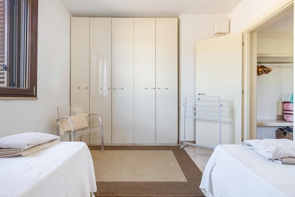 A bedroom with two beds, a wardrobe, a mirror, and a radiator.