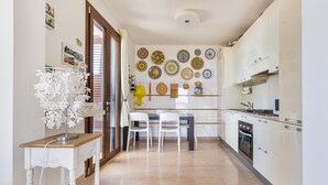 A kitchen with white cabinets, a dining table with chairs, and a wall decorated with plates.