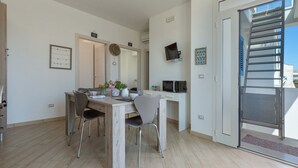 Een moderne keuken met een eethoek, een aan de muur bevestigde televisie en een schuifdeur naar een buitenruimte.