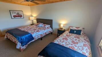 A bedroom with two beds, wooden ceiling, and a 'Stay Wild' sign.