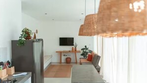 A modern kitchen with a built-in refrigerator, a dining area with a long table, and a TV mounted on the wall. - Comfortable and charming house 360m from the beach, Porto Seguro. (Porto Seguro)