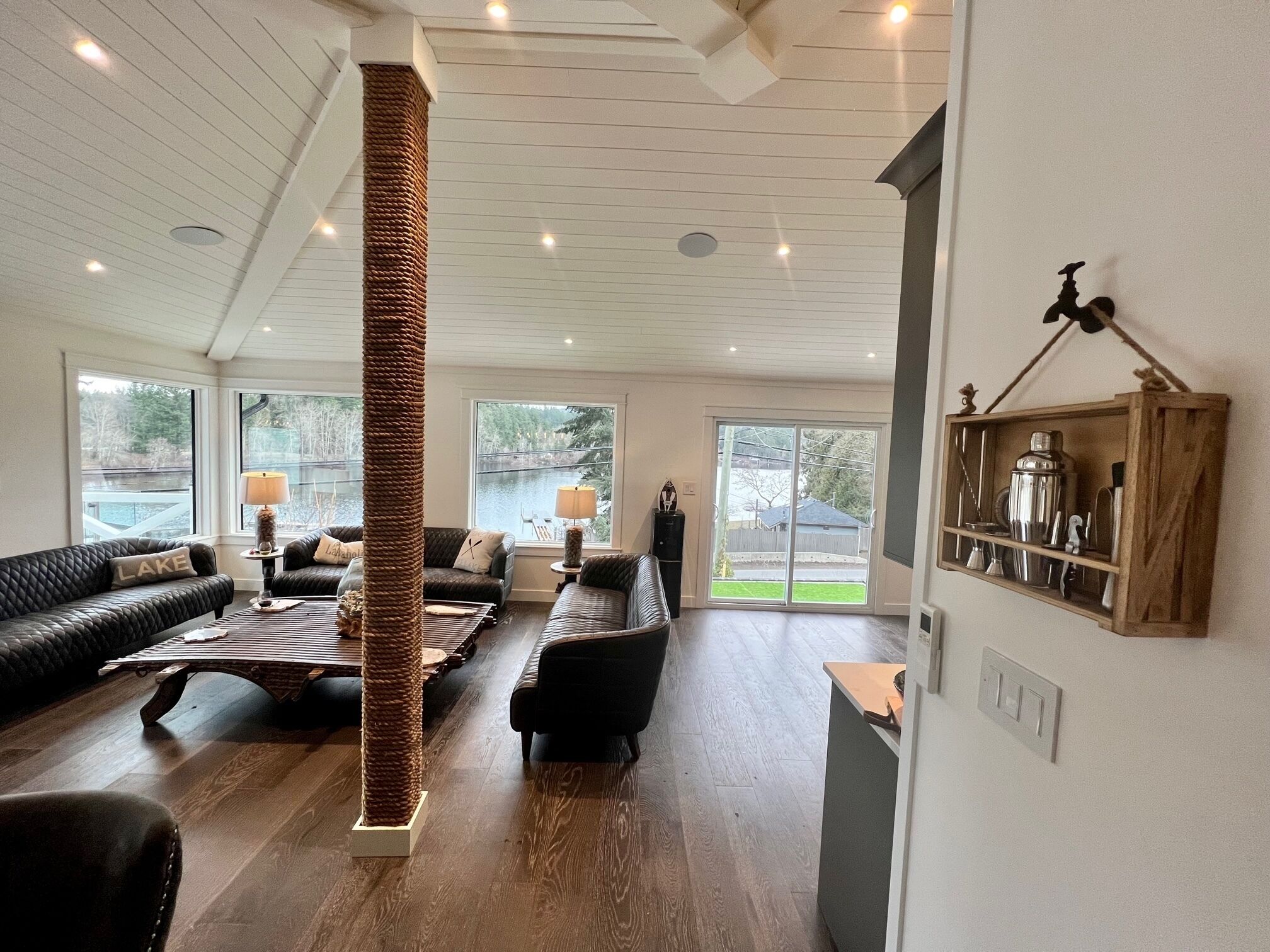 A spacious living room with a high ceiling, large windows, and a central column.
