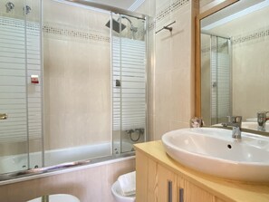 Bathroom features a large sink, glass shower enclosure, and a mirror above the sink.