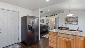 A modern kitchen with a stainless steel refrigerator, wooden cabinets, and a marble countertop.