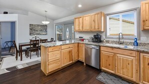 A modern kitchen with wooden cabinets, a stainless steel dishwasher, and a granite countertop.