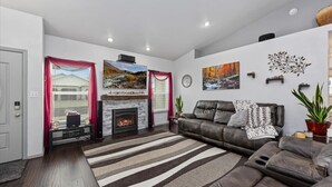 A modern living room with a fireplace, leather sofa, and artwork on the walls.