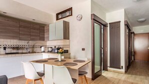 Een moderne keuken met een eethoek, met een houten tafel, witte stoelen en een vaas met bloemen.