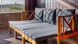 Een houten bed met een metalen frame in een kamer met een houten vloer en een groot raam.