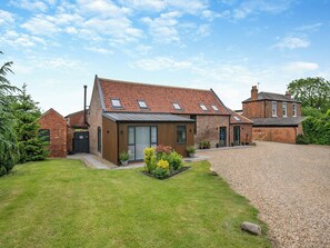 A brick house with a sloped roof, a small garden, and a gravel driveway. - The Warren - UK42858 (Skirlaugh)