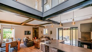 A modern kitchen with a large island, bar stools, and a dining area with a fireplace. - The Warren - UK42858 (Skirlaugh)