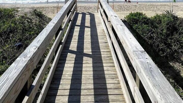 A wooden boardwalk leading to a beach with a flag on a pole. - Ocean & Sound Views, Game Room, Steps to Beach! (Surf City)