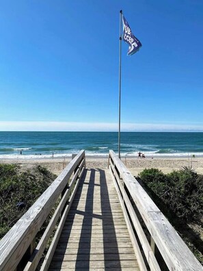 A wooden boardwalk leading to a beach with a flag on a pole. - Ocean & Sound Views, Game Room, Steps to Beach! (Surf City)