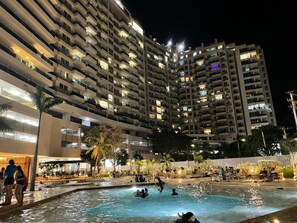 A nighttime view of a hotel with a swimming pool, multiple balconies, and outdoor seating areas. - Exclusive Apartasuites Reserva del Mar (Santa Marta)