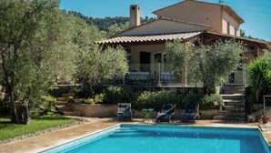 Uma villa com piscina, rodeada por vegetação exuberante e um céu azul límpido.