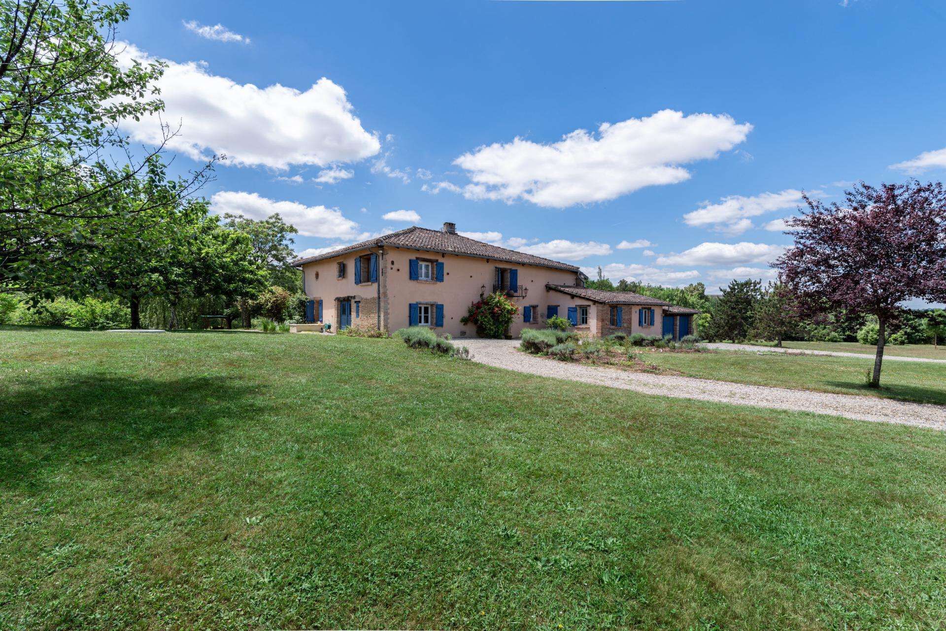 A two-story house with a paved driveway and a grassy lawn.