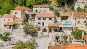 Un pueblo de piedra con tejados de teja, calles estrechas y una plaza central con una fuente.