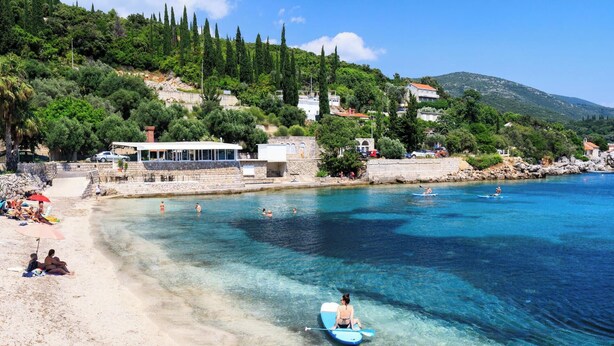 A beach with clear blue water, people swimming and paddling, and buildings in the background. - Ivana - Two Bedroom Villa, Sleeps 3 (Dubrovnik)