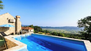 A swimming pool with a stone deck, a blue umbrella, and a view of the countryside. - Ivana - Two Bedroom Villa, Sleeps 3 (Dubrovnik)