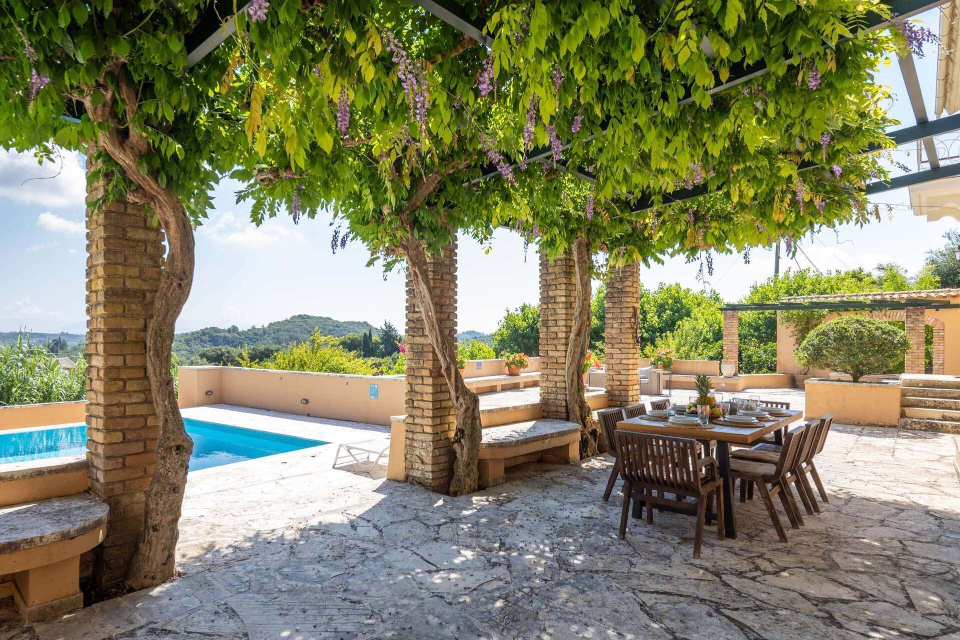 Terrassa exterior amb piscina, paviment de pedra i taula preparada per dinar.