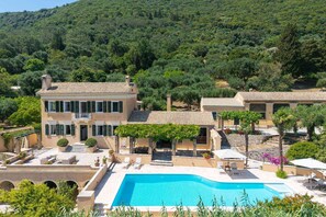 Een villa met zwembad, terras en uitzicht op het omliggende bos.