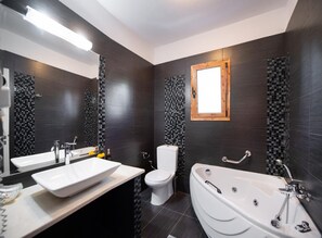 A modern bathroom with a large mirror, a white sink, a toilet, and a freestanding bathtub.