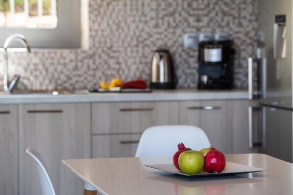 A modern kitchen with a white countertop, a kettle, and a coffee maker.