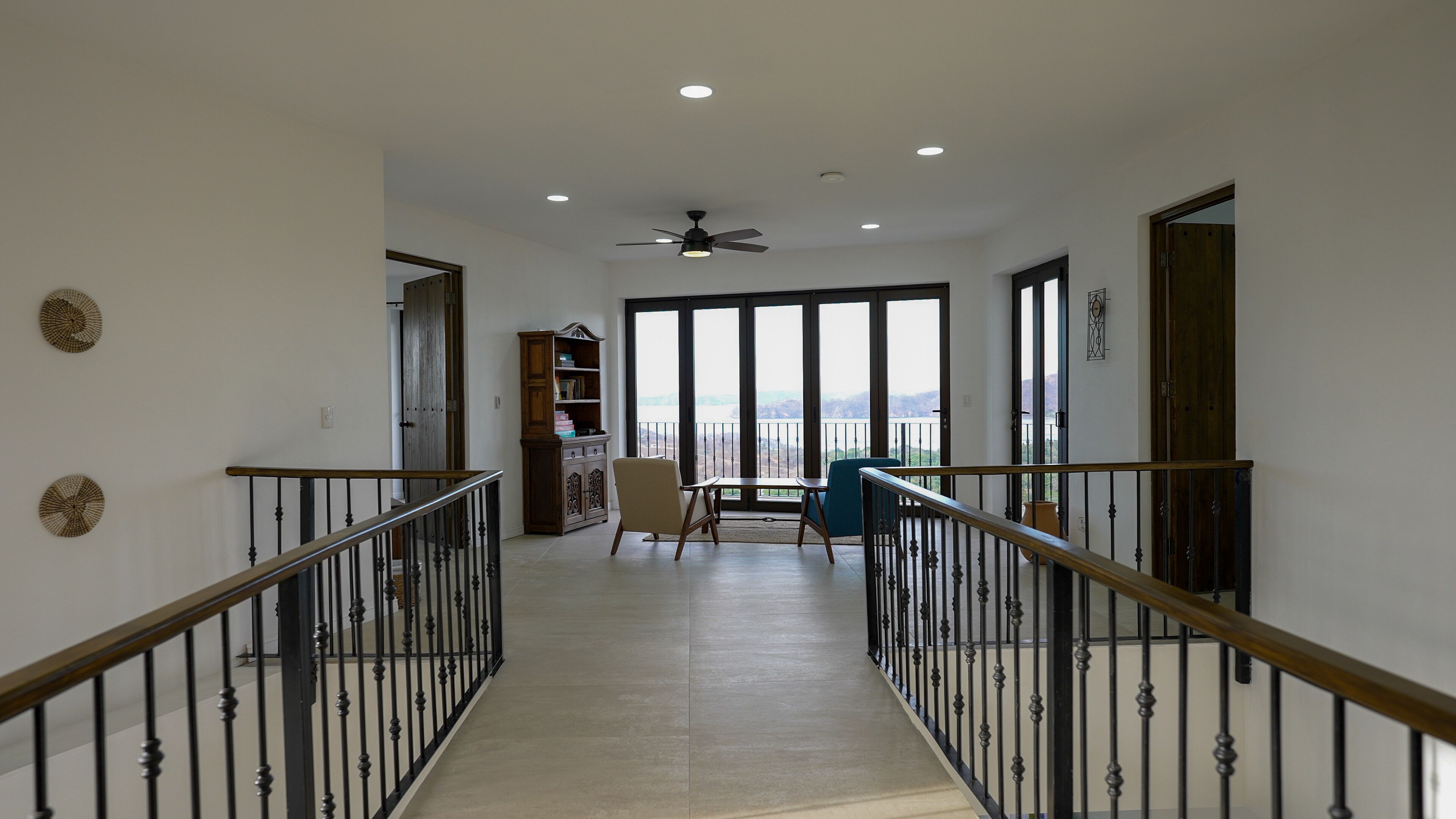 Um corredor amplo com varanda, corrimão de madeira e vista para o exterior.
