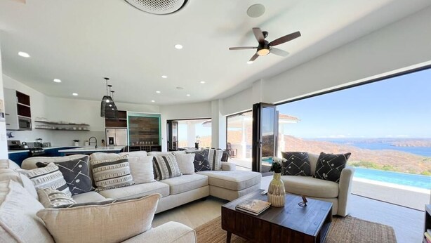 Una sala de estar moderna con un amplio sofá modular, una mesa de centro y vistas al paisaje desértico a través de grandes ventanales.