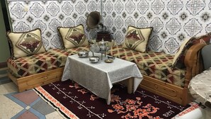 Una habitación tradicional con un conjunto de sofás, una mesita con juego de té, papel tapiz estampado y una alfombra decorativa.