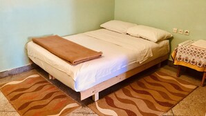 Una cama individual con una manta marrón, un cabecero de madera y un tapete estampado.