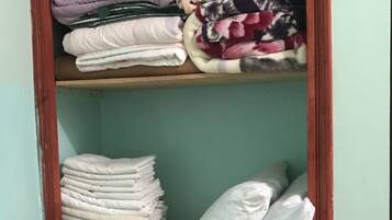 Een kast met opgevouwen kleding en een kussen.