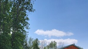 A wooden cabin with a porch, a small shed, and a grassy yard. - Lake Champlain Tiny House Paradise Private & Beautiful! (Alburgh)