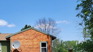 A wooden cabin with a satellite dish, a small shed, and a grassy yard. - Lake Champlain Tiny House Paradise Private & Beautiful! (Alburgh)